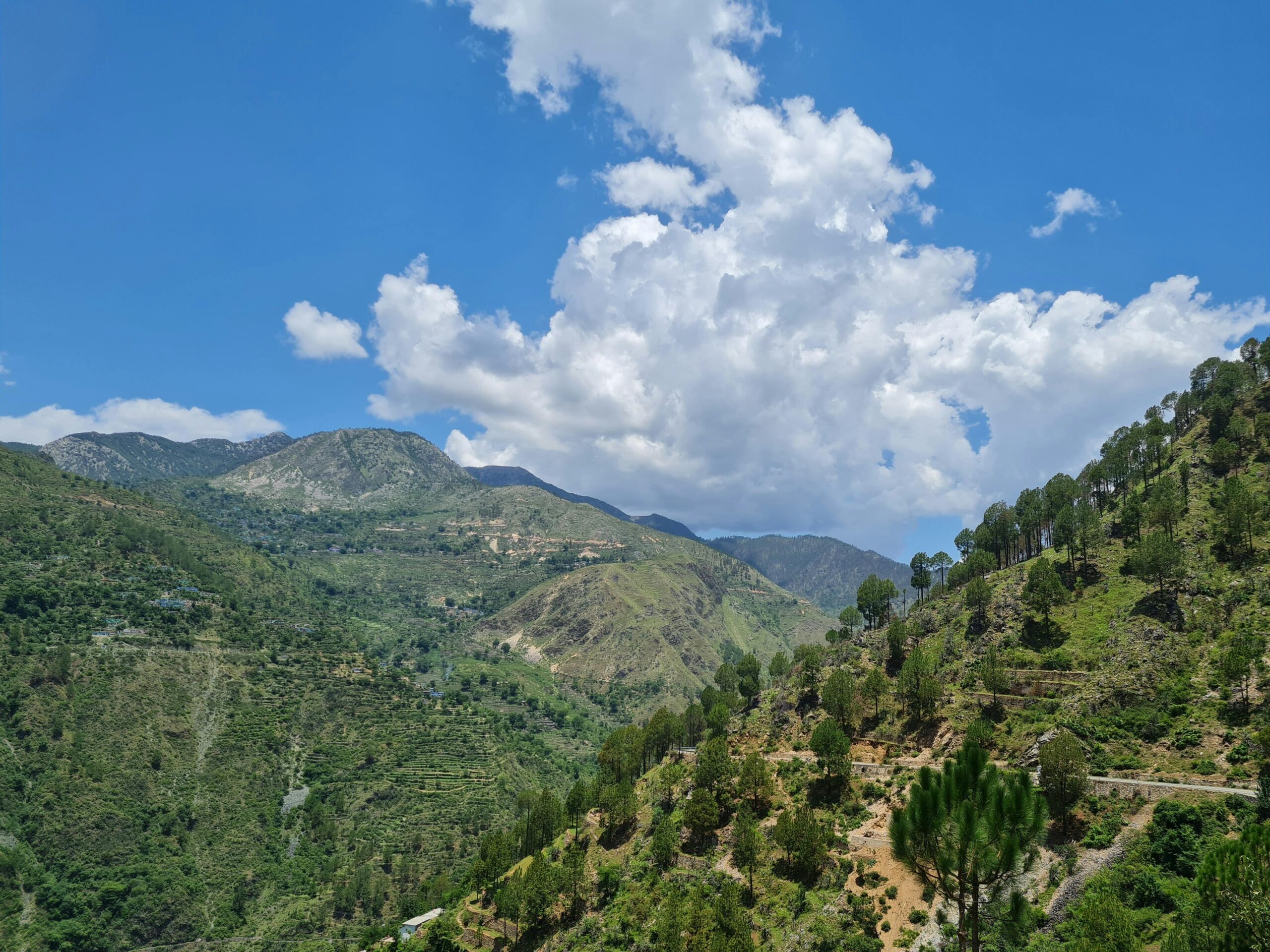 Scenic view of lush green mountains under a vibrant blue sky with clouds in India.